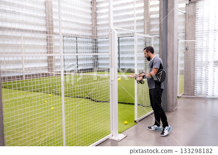 Male engaged in indoor tennis game on artificial grass court Male engaged in indoor tennis game on artificial grass court 133298182