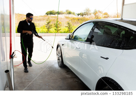 Young hispanic male washing white car at outdoor car wash station Young hispanic male washing white car at outdoor car wash station 133298185