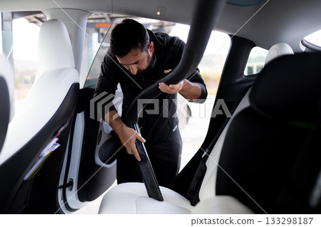 Male adult cleaning car interior with vacuum in modern vehicle Male adult cleaning car interior with vacuum in modern vehicle 133298187