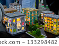 Prototype building printed on 3D printer from melted plastic. 3D-printed building prototype. A house created on 3D printer with green walls, gray roof, and illuminated windows and balconies. 133298482