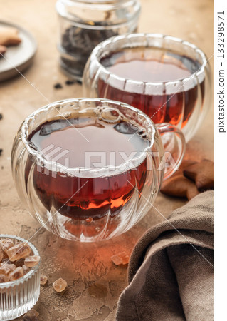 Black tea in two transparent glass cups on brown textured table background. Cozy breakfast teatime Black tea in two transparent glass cups on brown textured table background. Cozy breakfast teatime 133298571