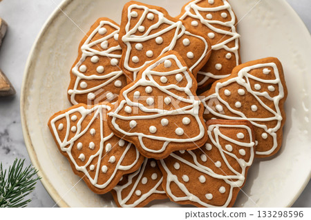 Gingerbread Christmas Cookies shaped like trees with icing decoration on a plate close up, top view. Christmas baking Gingerbread Christmas Cookies shaped like trees with icing decoration on a plate close up, top view. Christmas baking 133298596
