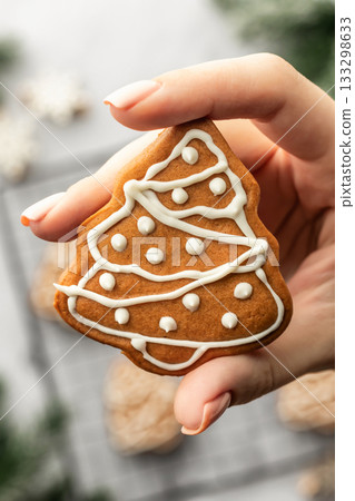 Freshly Baked gingerbread Christmas Cookie shaped like tree holded in hand close up. Christmas baking, top view Freshly Baked gingerbread Christmas Cookie shaped like tree holded in hand close up. Christmas baking, top view 133298633