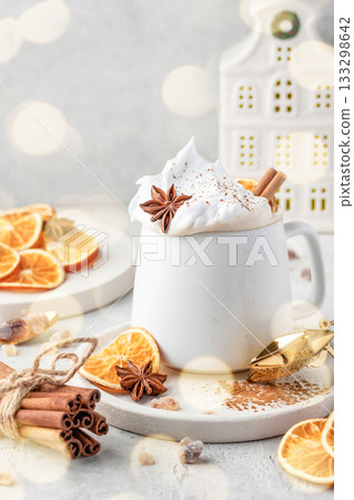 Hot cocoa drink with whipped cream, dried orange and spices in mug on white festive christmas table background 133298642