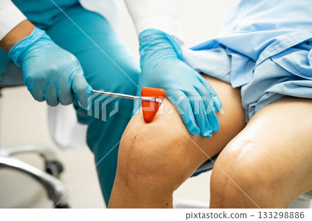 Asian doctor physiotherapist examining, massaging and treatment knee and leg of senior patient in orthopedist medical clinic nurse hospital. Asian doctor physiotherapist examining, massaging and treatment knee and leg of senior patient in orthopedist medical clinic nurse hospital. 133298886
