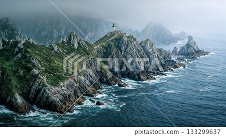 Dramatic coastal lighthouse perched on rocky cliffs above turbulent ocean waters with misty mountains in background. Moody atmospheric seascape with green grass and jagged rocks 133299637