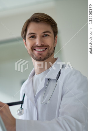 Male doctor standing next to portable white flipchart preparing for presentation 133300579