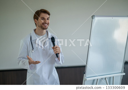 Male doctor standing next to portable white flipchart speaking into microphone 133300609