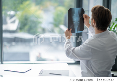 Young physician analyzing radiograph indoors near window 133300632
