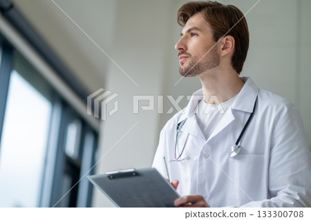 Young physician contemplating medical data while sitting Young physician contemplating medical data while sitting 133300708