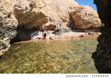 A woman swims on a secluded wild beach among the rocks 133301650