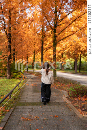 A young woman standing among fallen ginkgo leaves in an autumn park 133302355