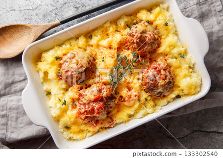 Homemade baked meatballs with mashed potatoes, cheddar, tomato sauce, and herbs in a baking dish. Horizontal top view Homemade baked meatballs with mashed potatoes, cheddar, tomato sauce, and herbs in a baking dish. Horizontal top view 133302540