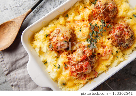 Baked beef meatballs with mashed potatoes, cheddar, tomato sauce, and thyme in a baking dish. Horizontal top view Baked beef meatballs with mashed potatoes, cheddar, tomato sauce, and thyme in a baking dish. Horizontal top view 133302541