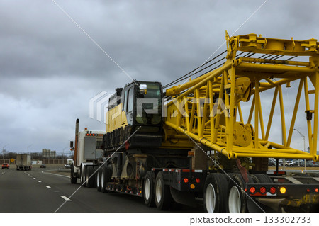 Heavy construction crane being transported on American highway in busy urban area 133302733