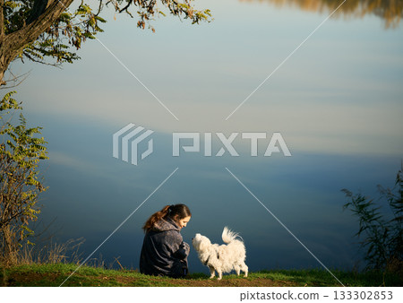 Happy woman resting with her cute dog outdoors enjoying time together. Happy woman resting with her cute dog outdoors enjoying time together. 133302853