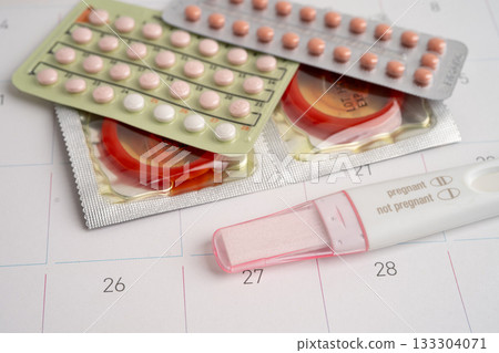 Pregnancy test and condom for female on calendar, ovulation day. 133304071
