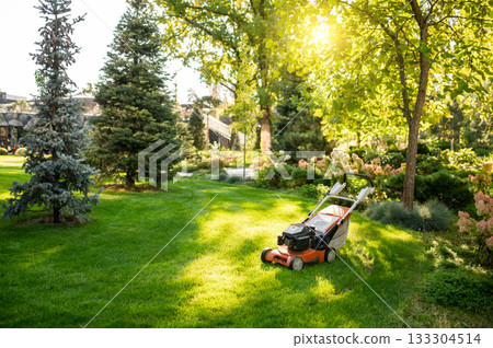 Lawn mower standing on freshly cut grass 133304514
