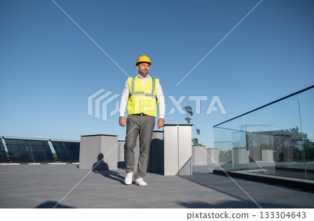 Worker in yellow vest monitoring performance of solar panels 133304643