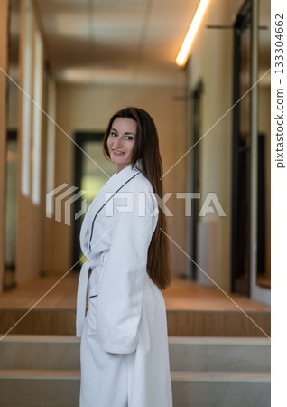 Beautiful young caucasian woman in white bath robe feeling contented and pleased 133304662
