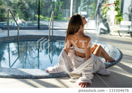 Long-haired young woman in white at the swimming pool in spa center Long-haired young woman in white at the swimming pool in spa center 133304676