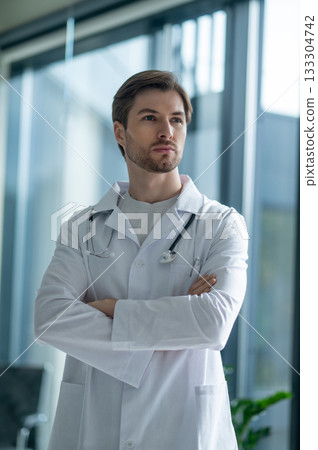 Confident young physician standing with crossed hands 133304742