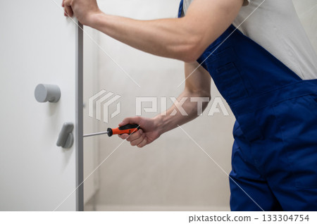 Maintenance worker fixing cubicle door handle using tools 133304754