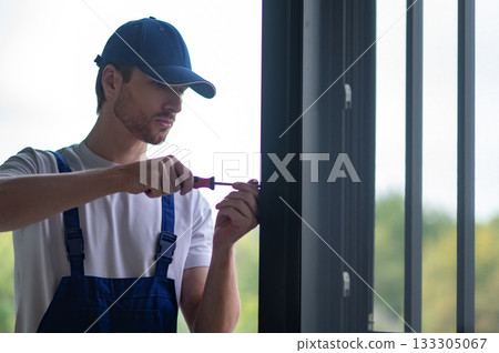 Worker fitting handles and locks on glass partition 133305067