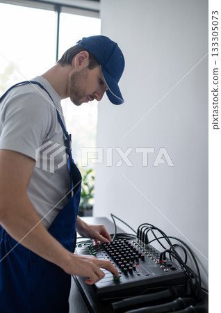 Technician adjusting stationary sound system in office 133305073