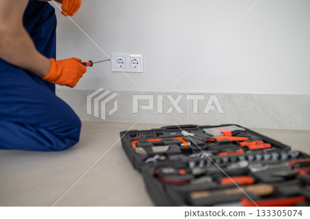 Male technician performing maintenance on power socket 133305074
