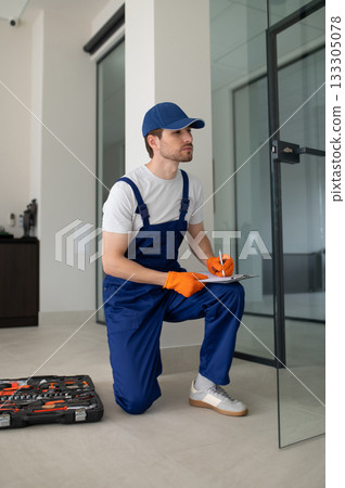 Technician installing handles and locks on glass doors Technician installing handles and locks on glass doors 133305078