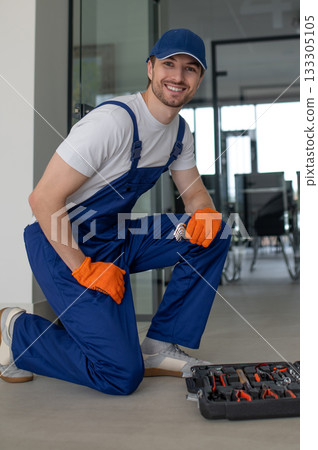 Technician installing handles and locks on glass doors 133305105