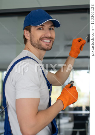 Craftsman installing hardware on glass door or partition Craftsman installing hardware on glass door or partition 133305128