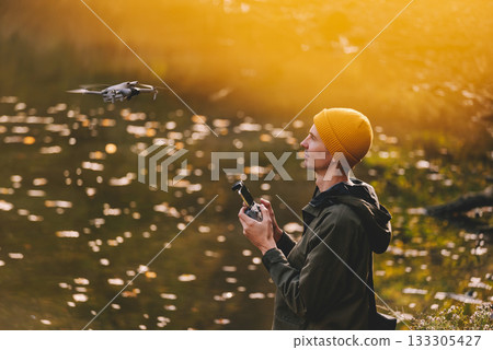 Man Flying Drone against Autumn Lake 133305427