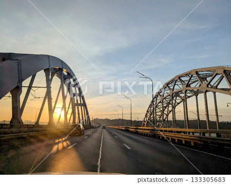 The metal structures of the road bridge in the rays of the setting sun The metal structures of the road bridge in the rays of the setting sun 133305683