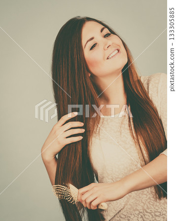 Happy woman brushing her hair 133305885