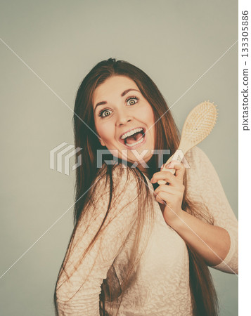 Happy woman brushing her hair Happy woman brushing her hair 133305886