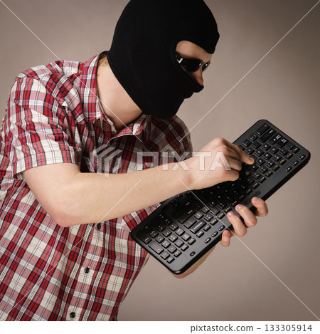 Man wearing balaclava holding keyboard 133305914