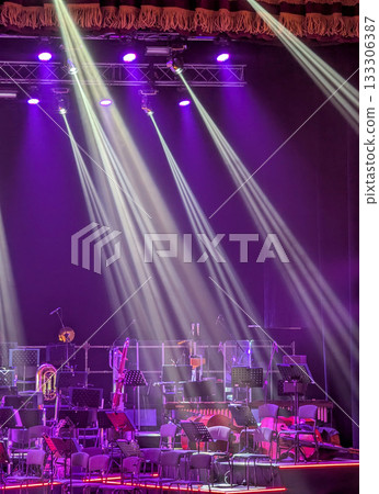 Multicolored beams of stage lighting illuminate the stage of the hall before the performance 133306387