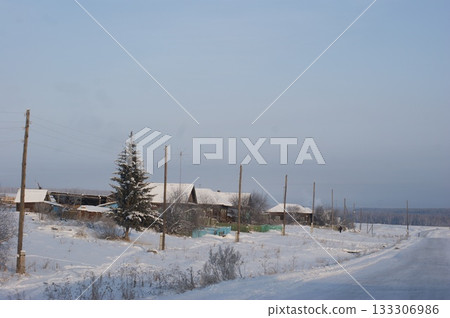The photograph depicts old houses in a Siberian village, an old fence, and snowdrifts The photograph depicts old houses in a Siberian village, an old fence, and snowdrifts 133306986