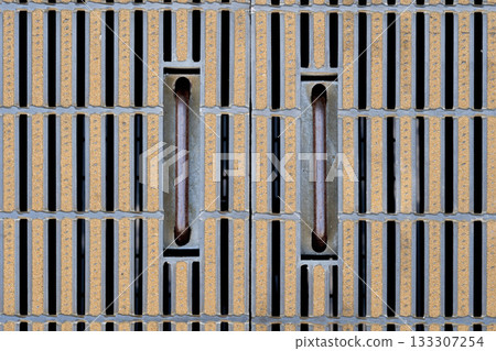 A close-up of a stylish metal grating. A grid-like gutter cover and a regular pattern. A close-up of a stylish metal grating. A grid-like gutter cover and a regular pattern. 133307254