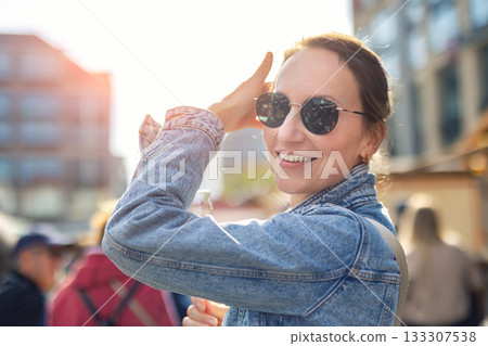 Portrait young adult pretty happy woman woman enjoy have fun walking city street war sunny evening. Denim jacket floral dress sunglasses create vibrant atmosphere filled with festive energy Portrait young adult pretty happy woman woman enjoy have fun walking city street war sunny evening. Denim jacket floral dress sunglasses create vibrant atmosphere filled with festive energy 133307538