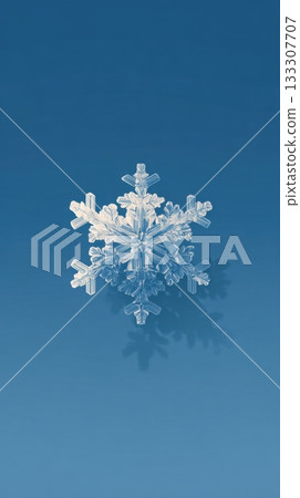 A single detailed ice snowflake floats against a smooth blue background A single detailed ice snowflake floats against a smooth blue background 133307707
