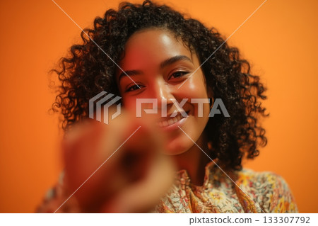 Smiling Young Woman Playfully Gestures at the Camera in Vibrant Setting 133307792