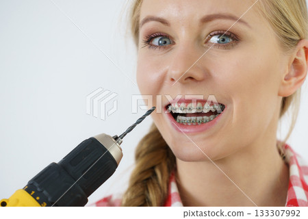 Woman with braces using drill on her teeth Woman with braces using drill on her teeth 133307992