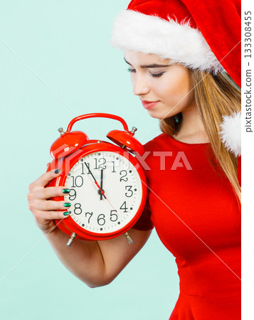 Woman wearing Santa Claus costume holding clock Woman wearing Santa Claus costume holding clock 133308455
