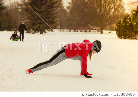 Woman wearing sportswear exercising outside during winter Woman wearing sportswear exercising outside during winter 133308490
