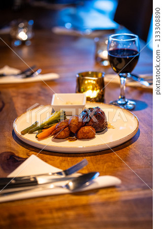 Beef steak meat with vegetables and sauce served with red wine and candles 133308890