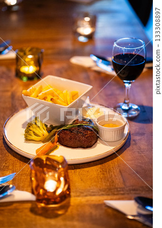 Beef steak meat with fried fryes vegetables and sauce served with red wine and candles 133308897