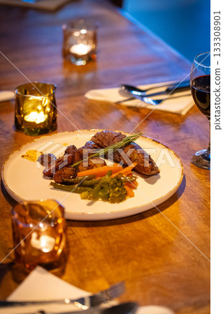 Beef steak meat with vegetables and sauce served with red wine and candles 133308901